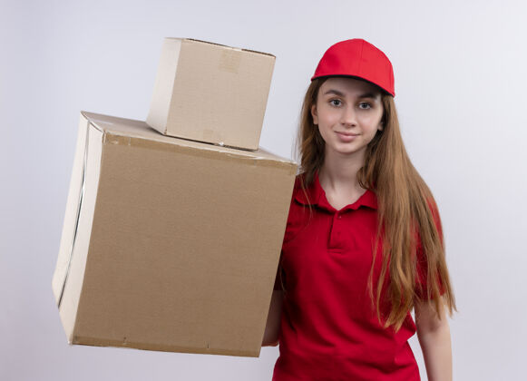 盒子穿着红色制服的年轻送货女孩在隔离的白色墙上拿着箱子女孩抱着制服