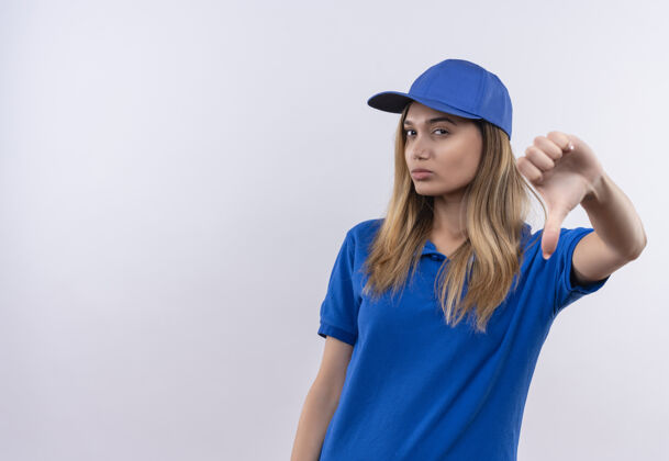 思考年轻的送货员穿着蓝色制服 戴着帽子 把拇指放在白色的墙上 留着复印空间拇指女孩向下