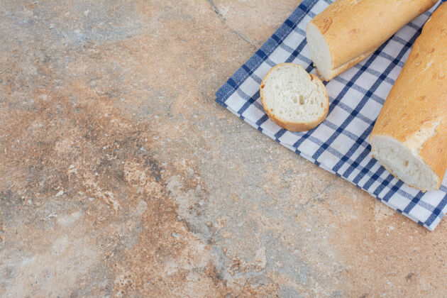 松脆新鲜的法式面包片在条纹桌布上食品面包桌布