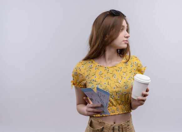 太阳镜年轻的旅行女孩头戴太阳镜 拿着飞机票和塑料咖啡杯 站在隔离的白色墙壁上看侧面图中的票轮廓杯子塑料