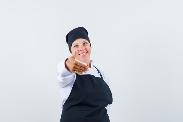 烹饪穿着黑色厨师制服的金发女人把手伸向镜头 看起来很漂亮 正对着镜头干净护理新鲜