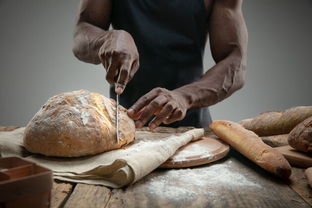 产品非洲裔美国人用菜刀切新鲜面包的特写镜头木材厨房纯