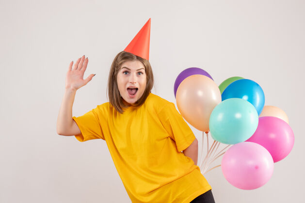 喜悦年轻的女性把彩色的气球藏在白色的背上回来情绪聚会