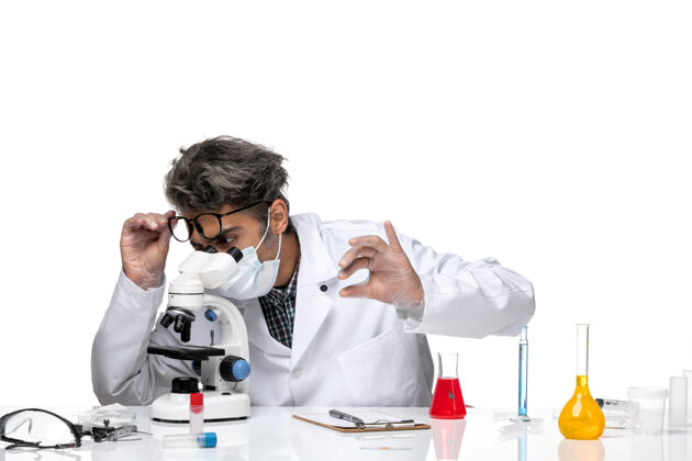 技师前视图中年科学家穿着医疗服通过显微镜检查小样本科学科学观察