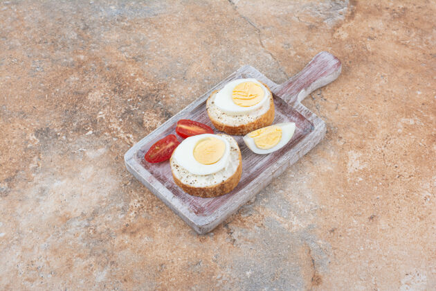 面包在木板上放上煮鸡蛋和西红柿片的面包片切片西红柿鸡蛋