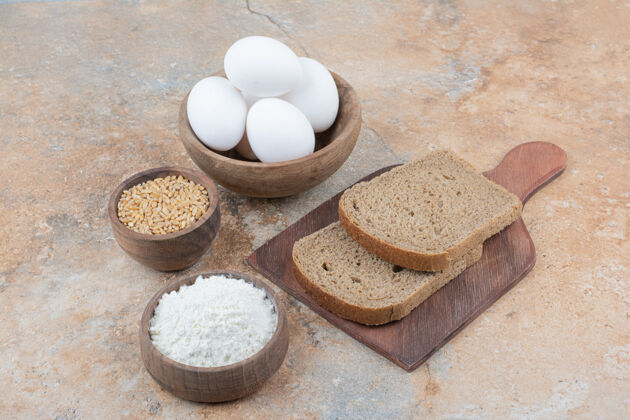 鸡蛋面包片 鸡蛋碗 面粉和大麦放在大理石表面木头美味面包房