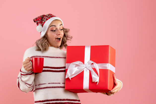 购物年轻的女性拿着圣诞礼物和一杯粉红色的茶圣诞节粉色举行