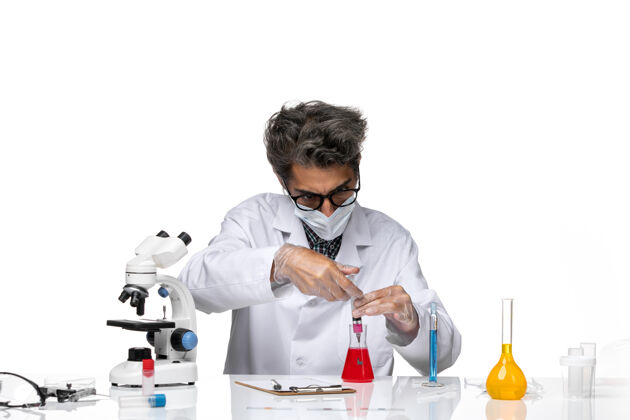正面正面图身着白色医疗服的中年科学家正在用溶液填充注射剂科学注射实验室