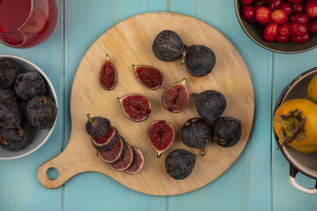 厨房新鲜的黑色任务无花果在一个木制厨房板与柿子水果在一个蓝色的木制墙上碗顶视图食品新鲜成熟