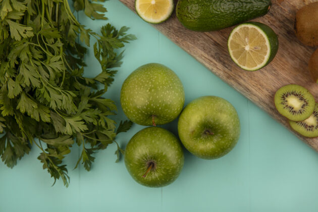 农业蓝色墙壁上的木制厨房板上健康的绿色苹果 鳄梨 酸橙和猕猴桃的俯视图酸橙猕猴桃水果