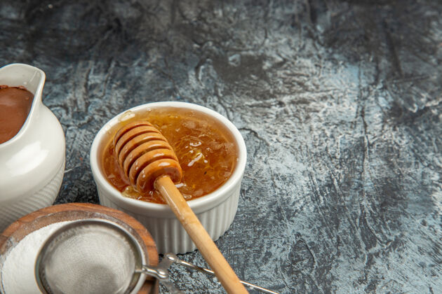 视图正面图甜甜的蜂蜜加糖在黑暗的表面甜甜的蜂蜜甜甜的蜜蜂勺子热的糖