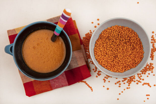 碗新鲜扁豆在碗上的顶视图 橙色扁豆汤在碗上 格子布上 勺子在白色墙上饮食新鲜检查