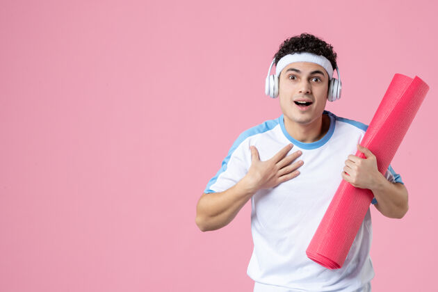 运动正面图穿着运动服的年轻男性 粉色墙上有瑜伽垫垫子微笑正面