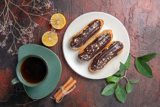 深色顶视图一杯茶配上美味的eclairs黑桌糖饼干甜点甜餐厅黄铜美味