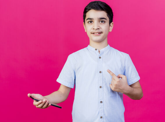 男孩印象深刻的小男孩拿着手机看着前面指着隔离在粉红色墙上的一侧脸站着年轻人