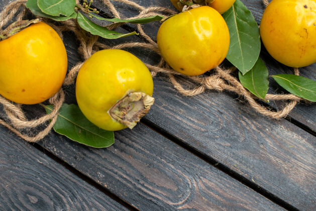 黄色顶视图木桌上新鲜甜甜的柿子 成熟水果的味道健康食物成熟