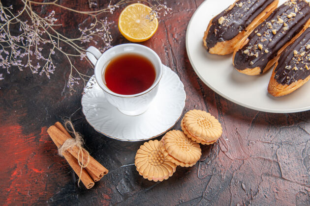 早餐顶视图一杯茶与饼干和eclairs在黑暗的地板糖茶饼干甜杯子盘子饼干