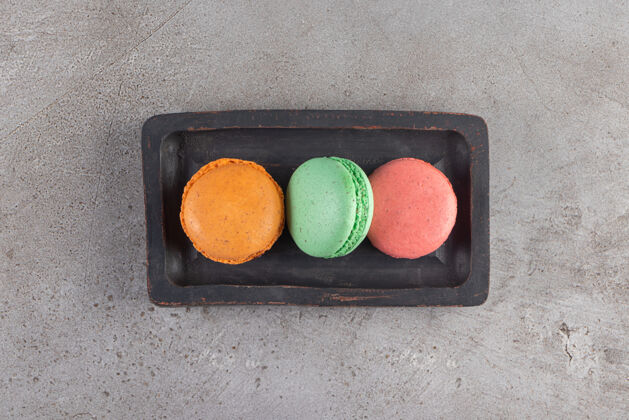 彩色不同颜色的通心粉饼干放在深色的木板上甜点饼干面包房