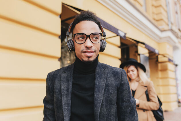 真诚戴着眼镜的梦幻非洲男人站在街上时尚黑人戴着耳机听音乐的户外照片街道帅气休闲