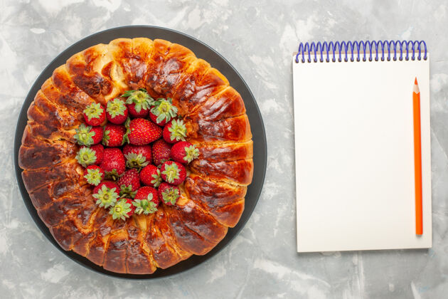 糕点顶视图美味的草莓派与新鲜的红色草莓和白色表面上的记事本派盘子餐