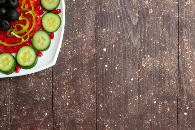 沙拉俯视图：棕色乡村书桌上的盘子里放着橄榄黄瓜片 营养沙拉蔬菜维生素健康饮食新鲜盘子