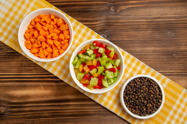 餐厅顶视图棕色木制餐桌上的调味品甜椒切片蔬菜餐食品健康沙拉晚餐生的蔬菜