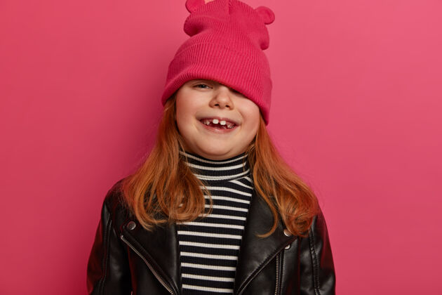 时尚漂亮女孩的肖像从帽子下看 玩捉迷藏 笑容灿烂 心情乐观 穿着时髦的衣服 有快乐的童年 周末和妈妈一起逛街感情微笑红发