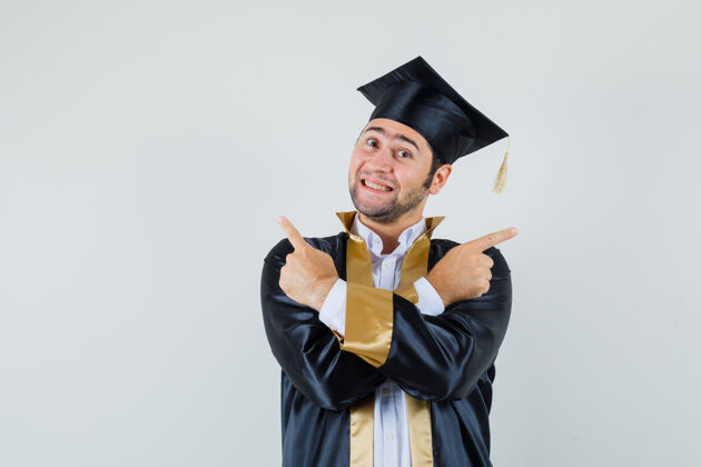 聪明年轻人指着远处的毕业生制服 看上去很乐观正面视图肖像成功毕业