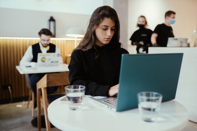 教育一位年轻漂亮的女士在便携式笔记本电脑上工作 迷人的女学生坐在咖啡馆里用上网本网络休息便携