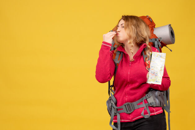 肖像俯视图中 戴着医用面罩的年轻旅行女孩正在收拾行李 手里拿着地图 做出完美的姿势举行行李收集