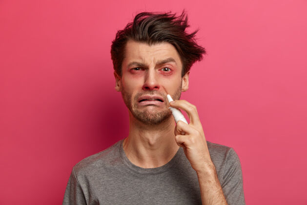 成人病人感冒 患有鼻炎或鼻塞 使用鼻喷雾剂 眼睛红肿 建议就医 想尽快康复 隔离在粉红色的墙壁上保健理念病毒疼痛滴落
