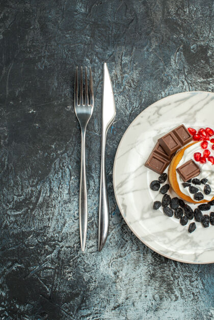 背景顶视图美味的奶油蛋糕和葡萄干在浅黑色的背景午餐餐具饼干