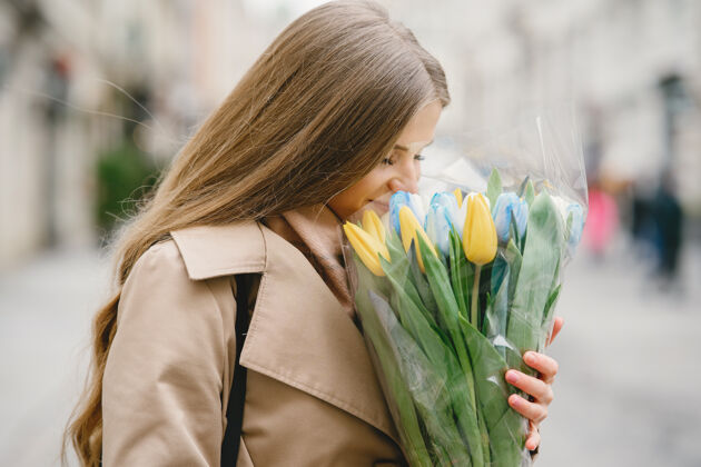 花束穿着棕色外套的漂亮女孩春城里的女人带着花束的女人站着年轻可爱