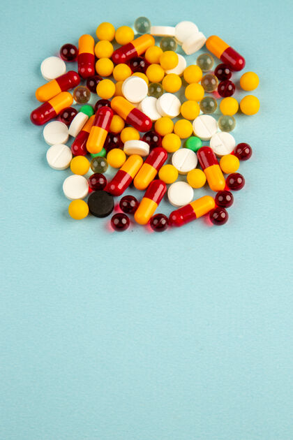顶部蓝色背景上的彩色药丸俯视图食品药品彩色