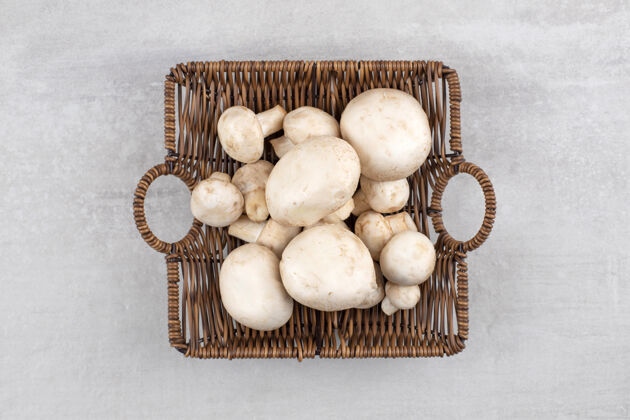 蘑菇石桌上放着一篮柳条装的鲜白蘑菇烹饪香菇有机