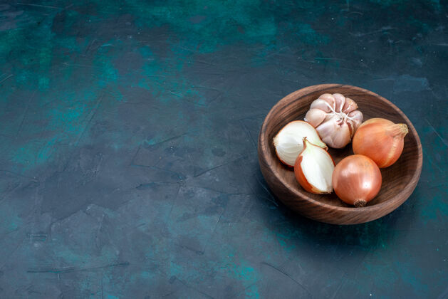 洋葱前视图洋葱和大蒜上深蓝色的桌子蔬菜餐食品健康食物碗配料