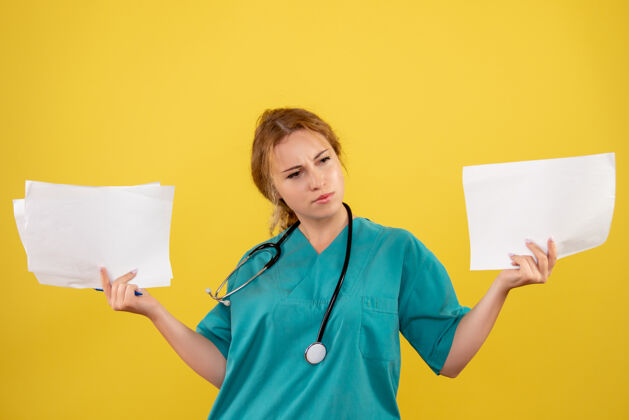 持有黄墙上穿着医疗服的女医生手持分析图健康护士分析