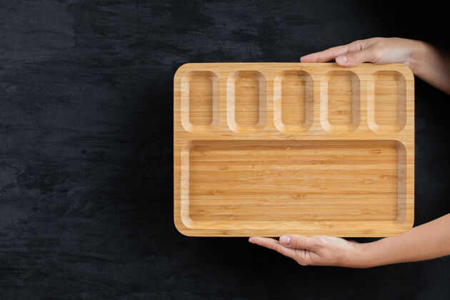 晚餐用手拿着一个方形的木盘餐具传统美味