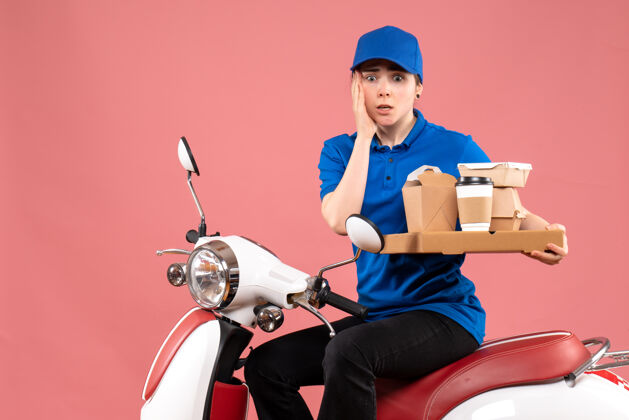 视图正面图女快递员带着食品包装盒和粉色工作服上的工人送食品自行车制服服务工作成人人