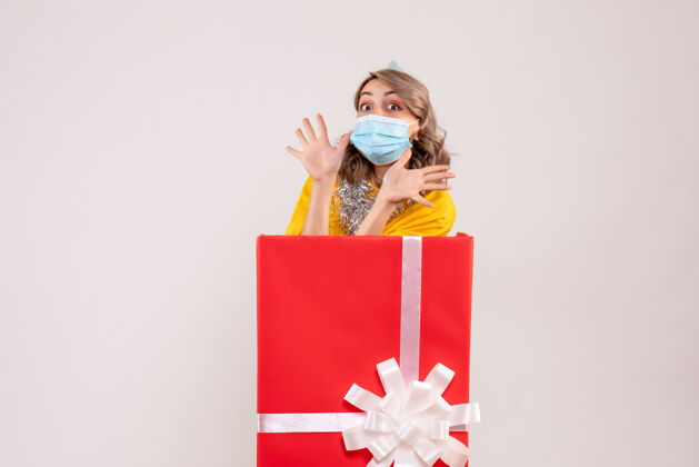 年正面图：戴着面具的红色礼品盒里的年轻女性购物圣诞节里面