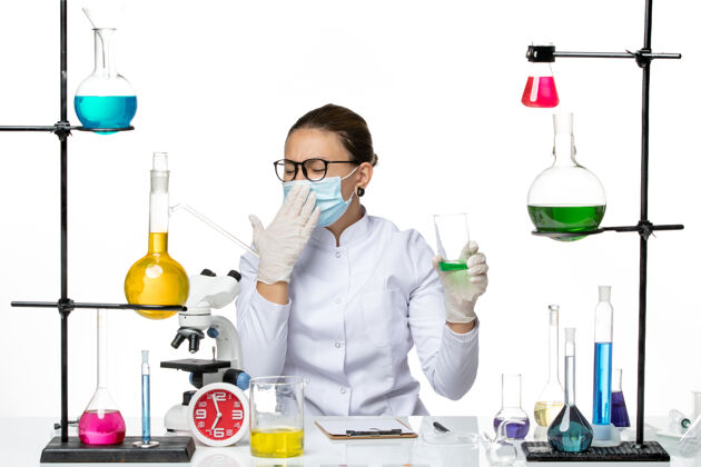 医学前视图穿着医疗服的女化学家 白色背景上戴着口罩饮用水飞溅实验室病毒化学冠状病毒烧杯科学喷溅