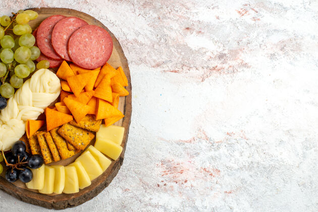 膳食顶视图不同的小吃cips香肠奶酪和新鲜葡萄在一个浅白色的空间水果葡萄奶酪