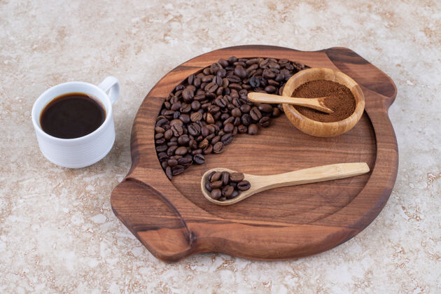 豆子在一盘咖啡豆和磨碎的咖啡粉旁边放一杯咖啡勺子杯子芳香