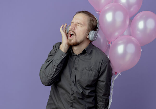 烦戴着耳机的恼怒帅哥站在紫色墙上 氦气球被隔离帅哥氦生日