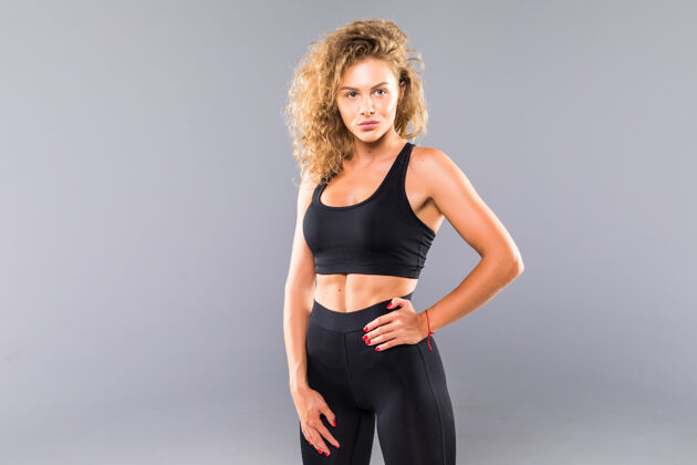 拳击性感的年轻女子的画像 她的手放在臀部健身女性 肌肉发达的身体准备戴上手套在灰色的墙上锻炼赛车力量健身房