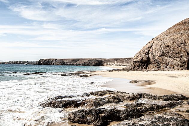 岩石阳光明媚的西班牙兰萨罗特海滩和蓝海的美丽照片蓝色棕色清晰