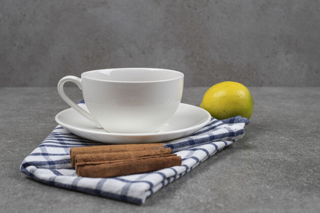 桌布一杯茶 肉桂棒和柠檬放在大理石表面新鲜健康肉桂