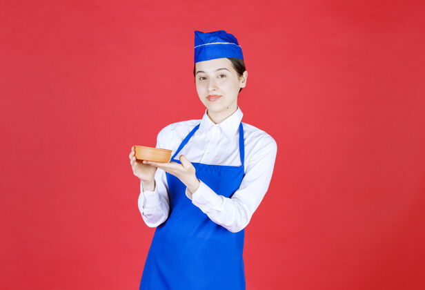 烹饪穿着蓝色围裙的厨师手里拿着一个陶碗女性休闲人类