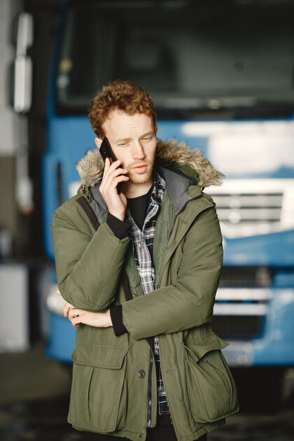 车辆穿着温暖的绿色夹克的男人卡车停在车库里解决物流问题卷发成人年轻人
