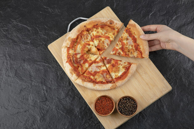 美味母手从木板上拿一块水牛披萨辣食物比萨饼